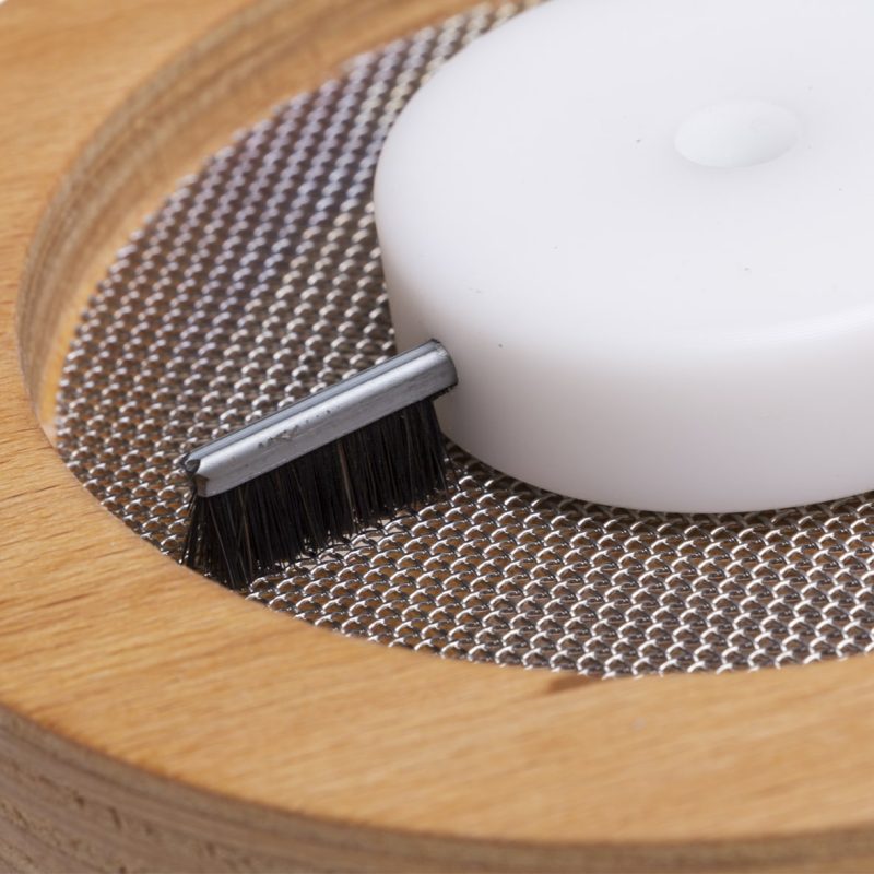 Close-up of the flour sifter brushes sweeping flour over the mesh screen