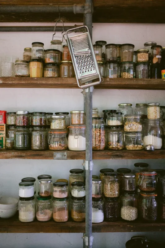 A pantry shelf of sealed jars holding grains, flour and pulses