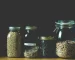 Wheat berries and other grains stored in sealed glass jars on a pantry shelf