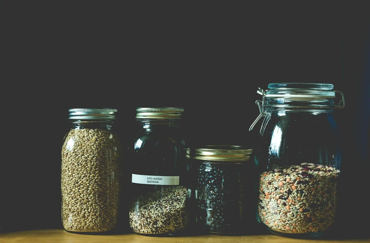 Wheat berries and other grains stored in sealed glass jars on a pantry shelf